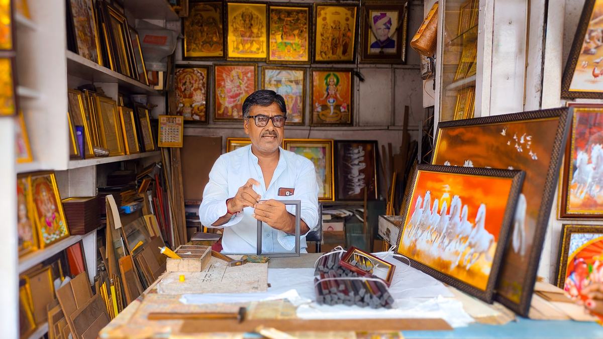 Indian shop owner at his frame workshop counter, a small business owner choosing where to advertise