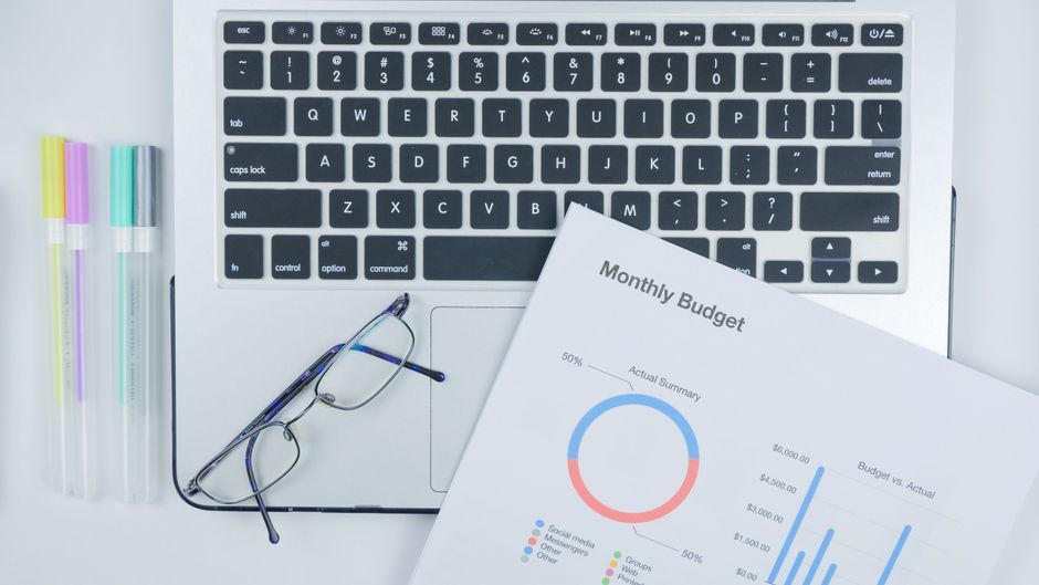 Monthly budget sheet beside a laptop on a desk