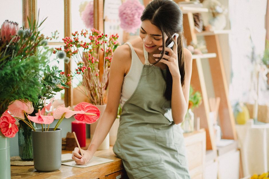 Small business owner checking her phone at a flower shop counter