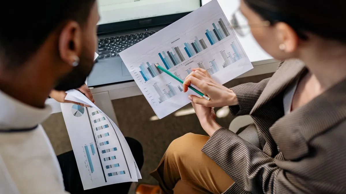 Two colleagues discussing data charts together in an office