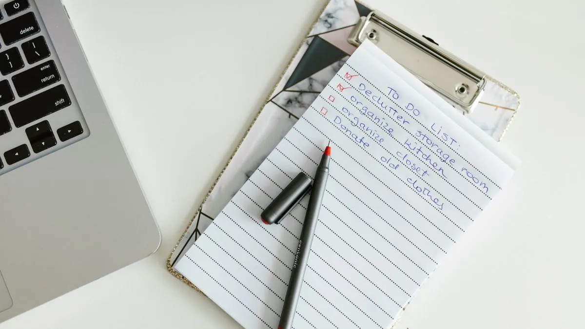 Clipboard with a neat checklist beside a laptop and a pen