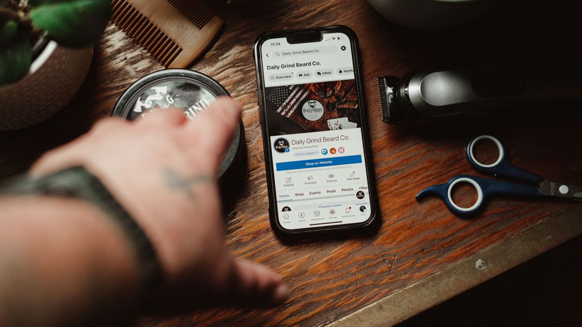 Business Facebook page open on a smartphone beside a barber's tools