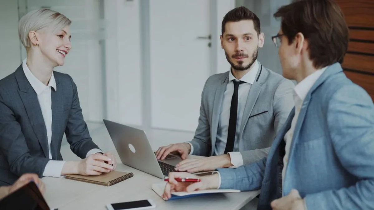 Colleagues in a meeting discussing sales leads around a laptop