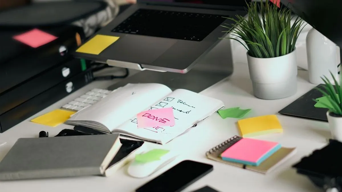 Desk with an open checklist notebook, sticky notes and a laptop for planning a workflow
