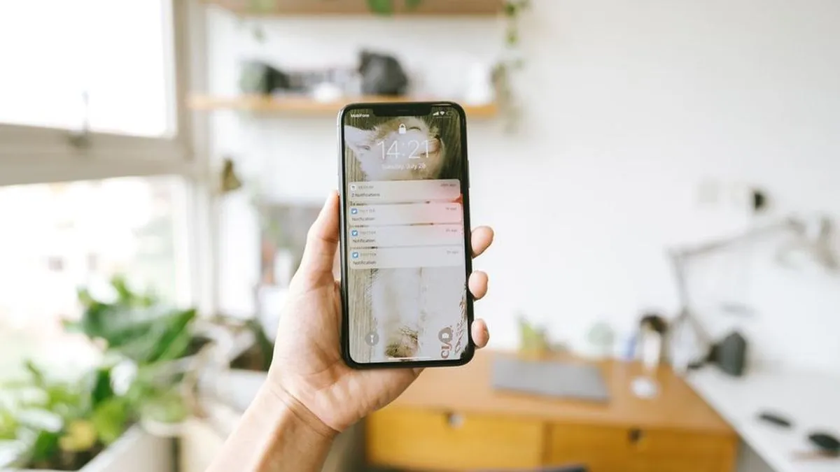 Hand holding a smartphone showing message notifications on the lock screen