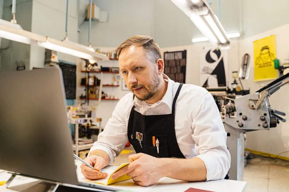 Small business owner working on laptop at a shop desk