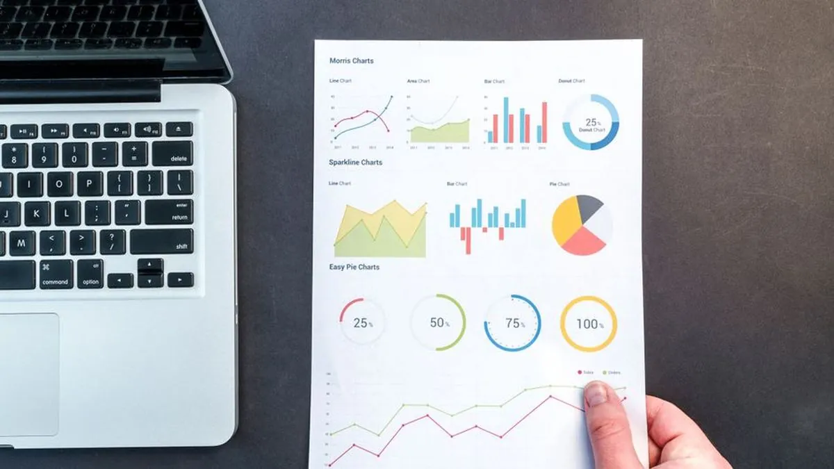 Printed report of line, bar and pie charts lying next to a laptop keyboard