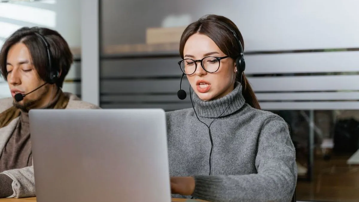Customer support team members wearing headsets and working on laptops