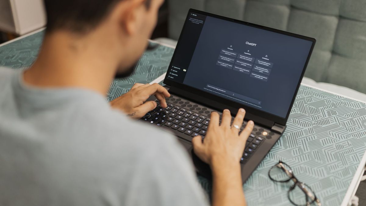 Person working on a laptop with a chatbot flow on screen