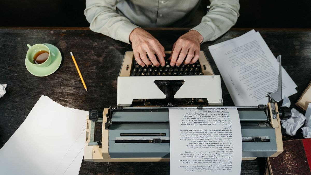 Writer at a desk with a typewriter, paper and coffee drafting content