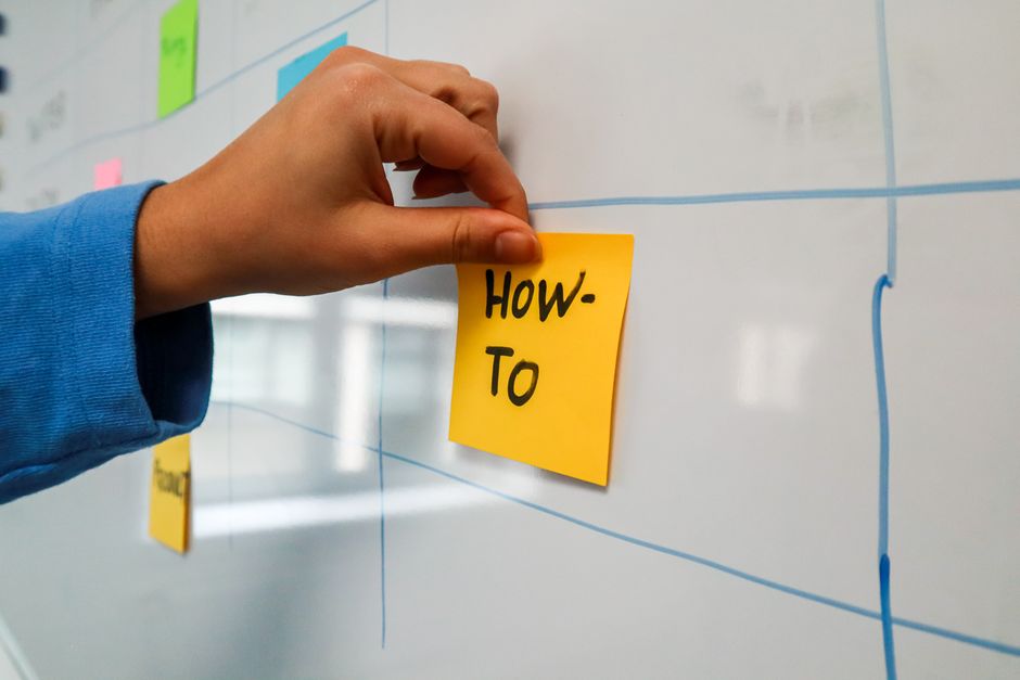Marketer placing a how-to topic note on an editorial content calendar board