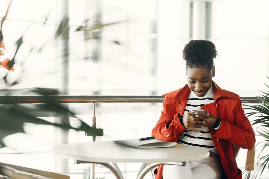 Woman checking a marketing email on her smartphone at a cafe table