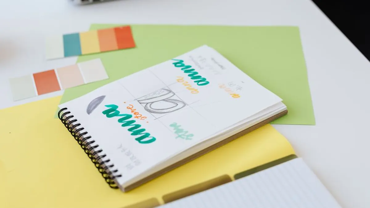 Color swatches and a sketch notebook with lettering ideas on a white desk