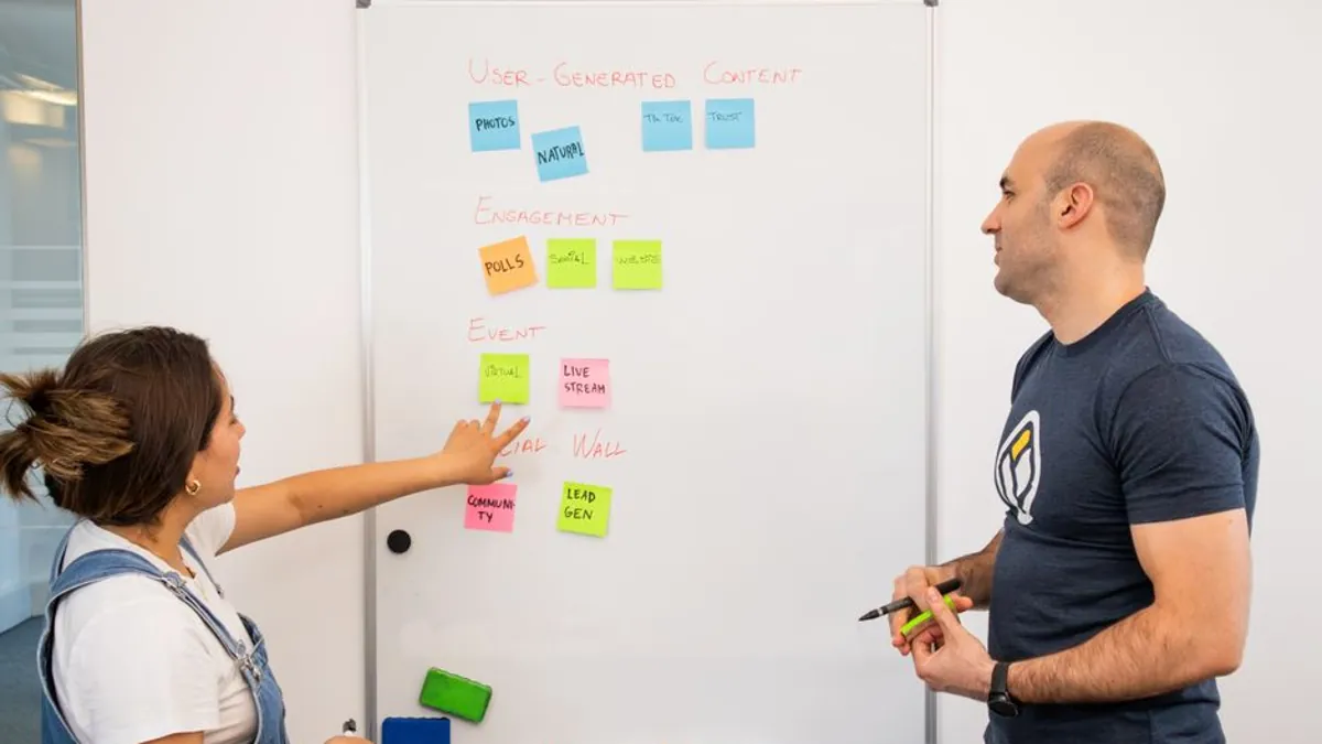 Two colleagues planning a strategy with sticky notes on a whiteboard
