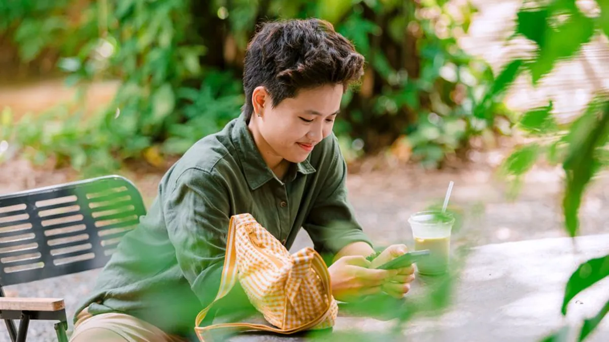Cafe owner checking customer messages on a smartphone at an outdoor table