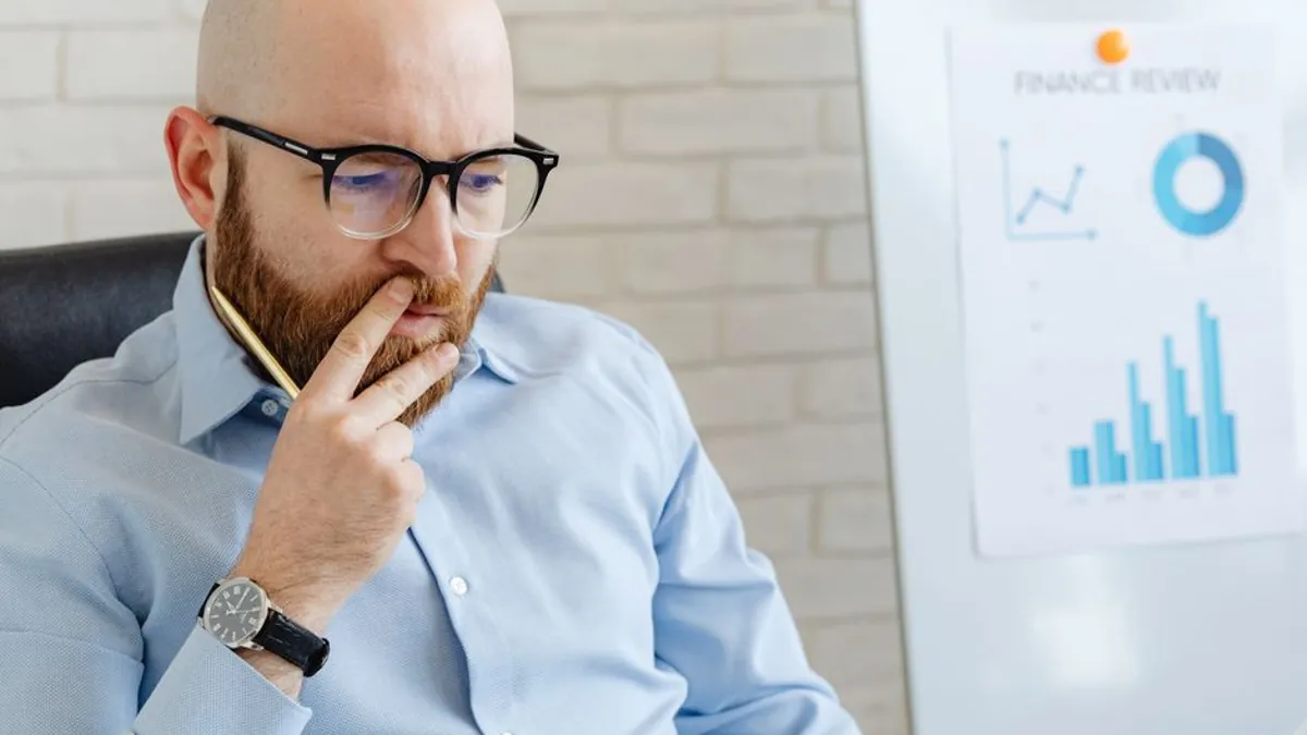 Business owner thinking over a finance review chart on a whiteboard