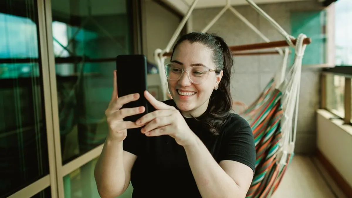 Woman smiling while taking a photo with her smartphone