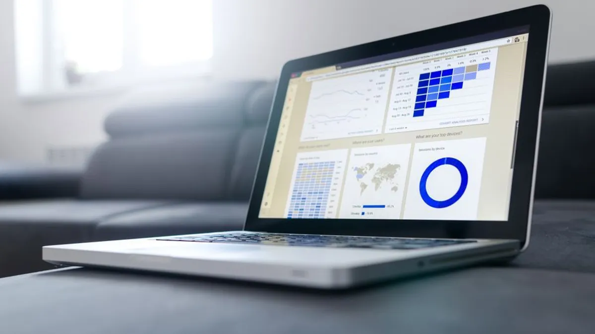 Laptop on a couch showing an analytics dashboard with charts