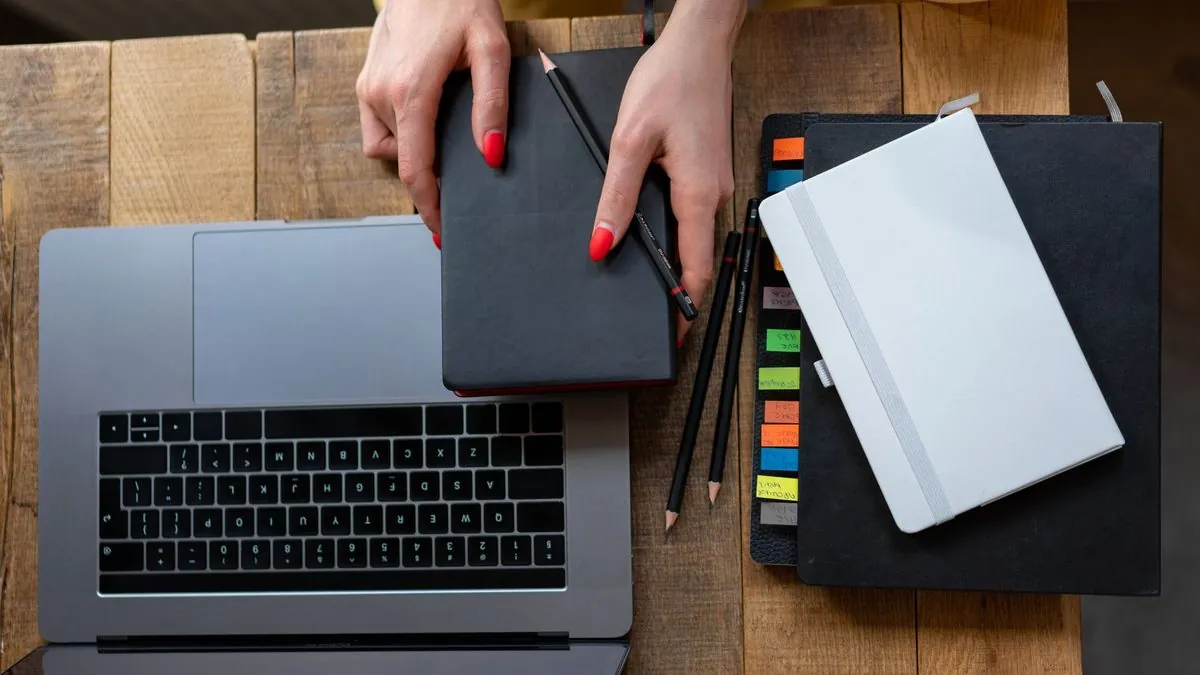 Overhead view of a desk with an open laptop, a planner and notebooks for planning email campaigns