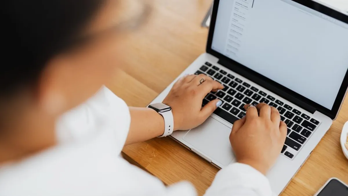 Woman typing on a laptop with an email inbox open on the screen