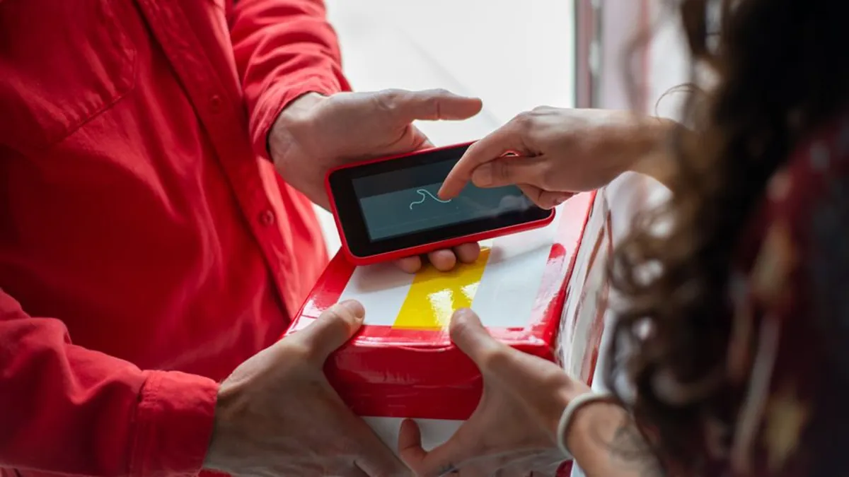 Courier handing over a parcel while the customer confirms delivery on a tablet