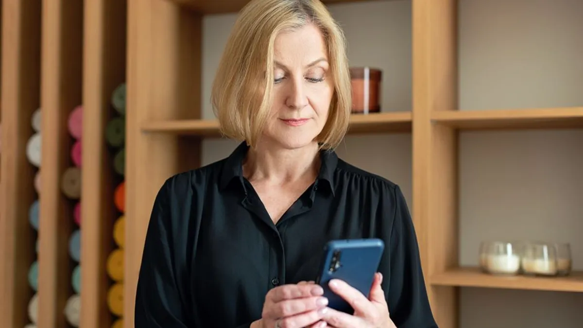 Woman in a black blouse reading an email on her smartphone