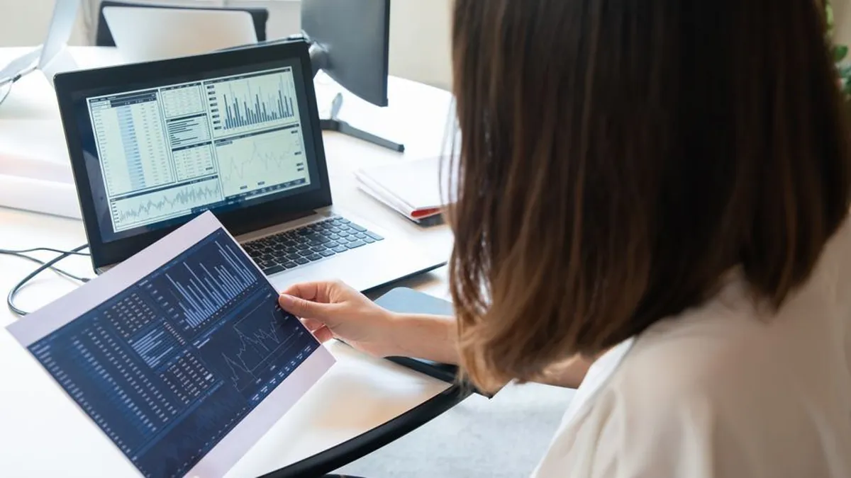 Business owner reviewing a printed performance report next to a laptop with charts