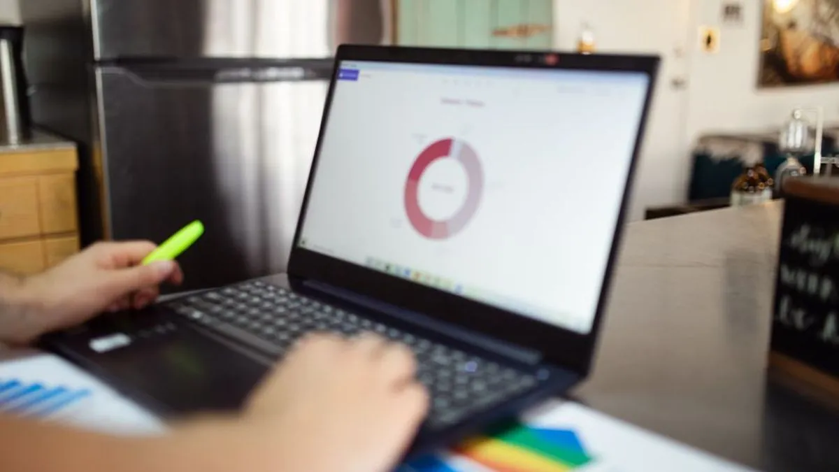 Laptop showing a chart on a desk beside printed performance graphs