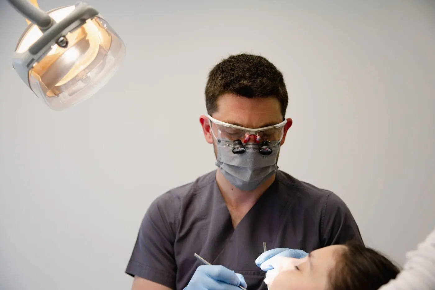 Clinician preparing a treatment for a patient under a surgical light