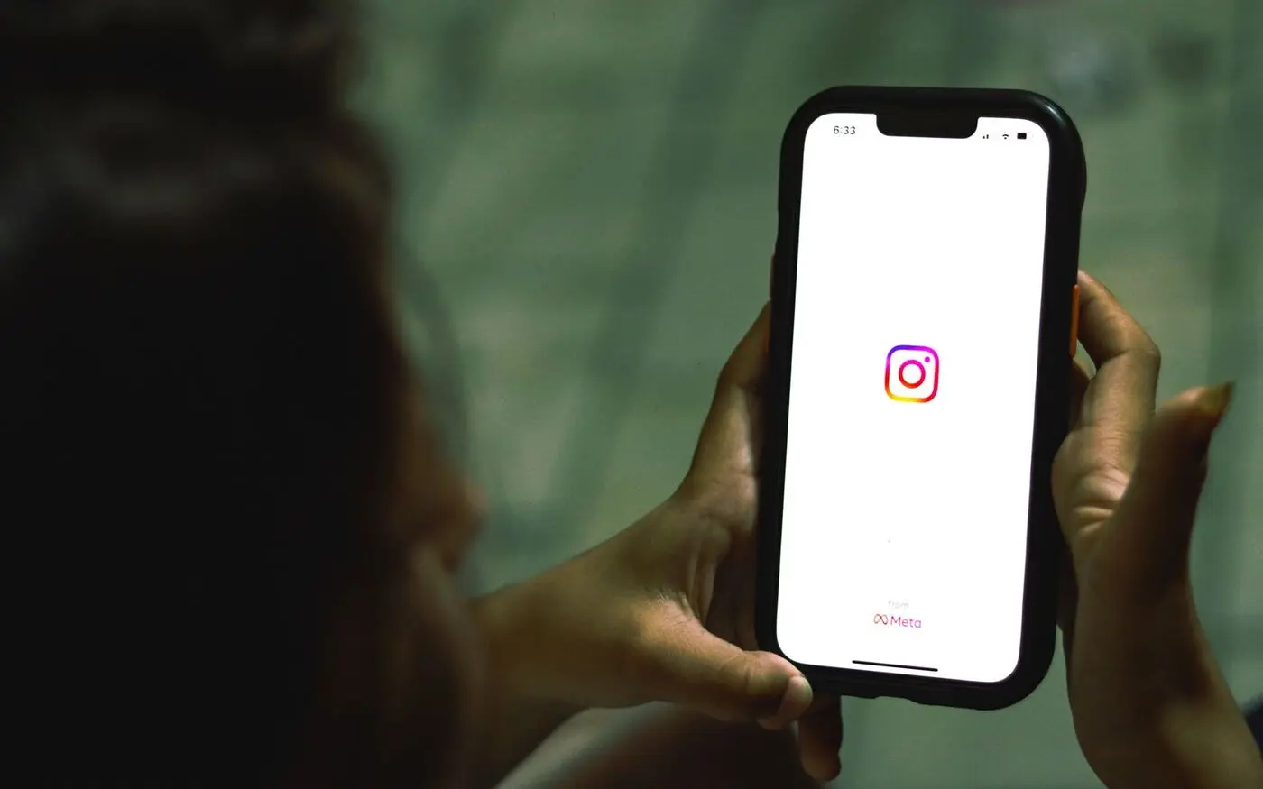 Hands holding a phone showing the Instagram app